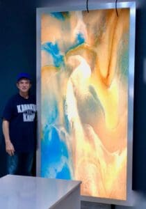 A man standing next to an art work.