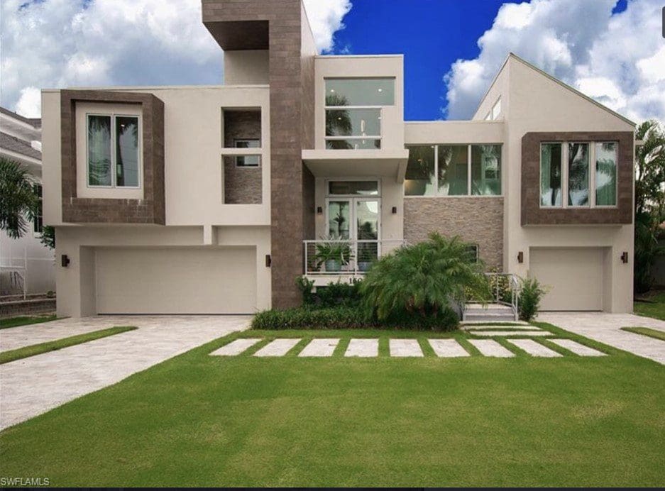 A large modern house with a driveway and lawn.